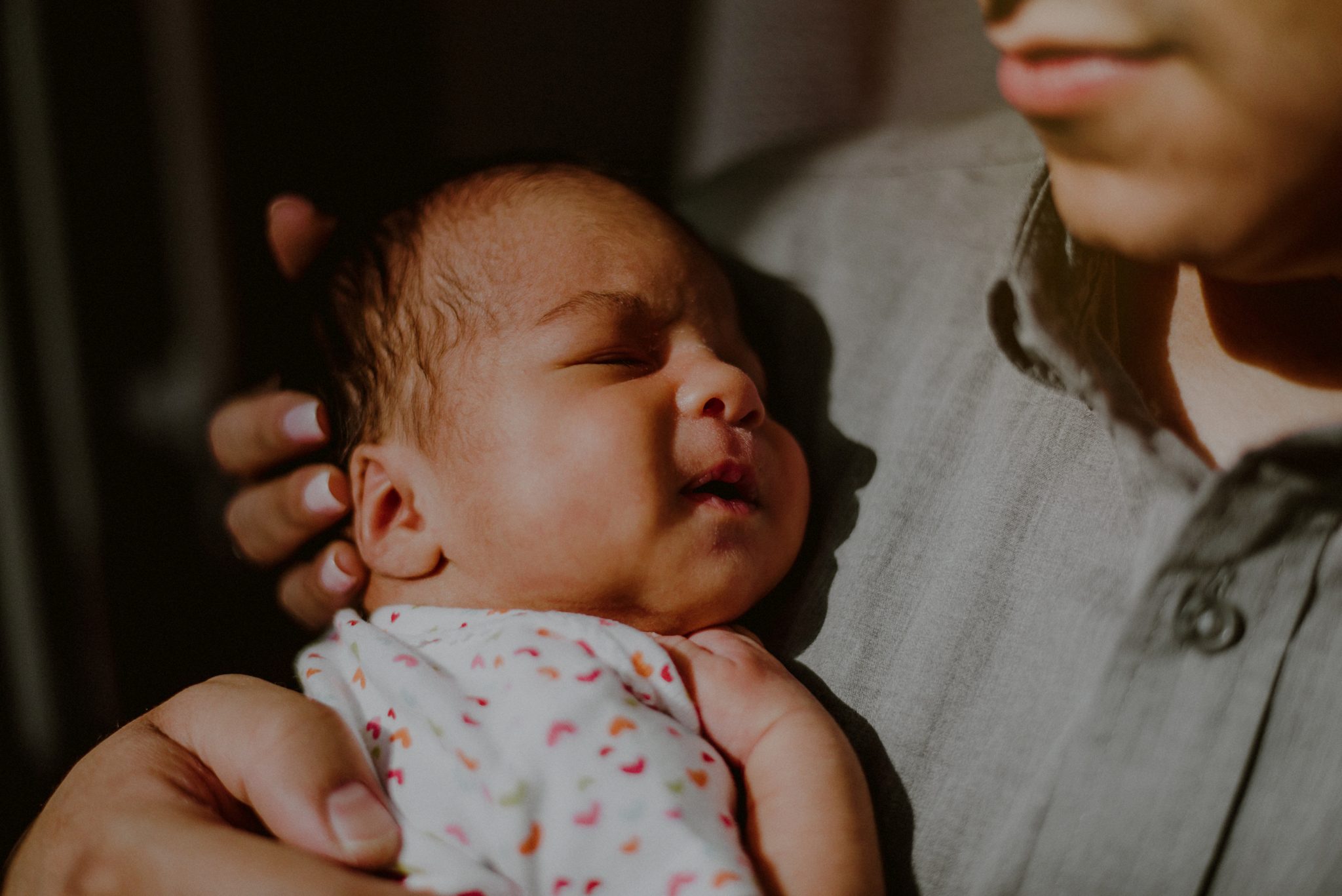 closeup of baby's face sleeping on father's chest in the light