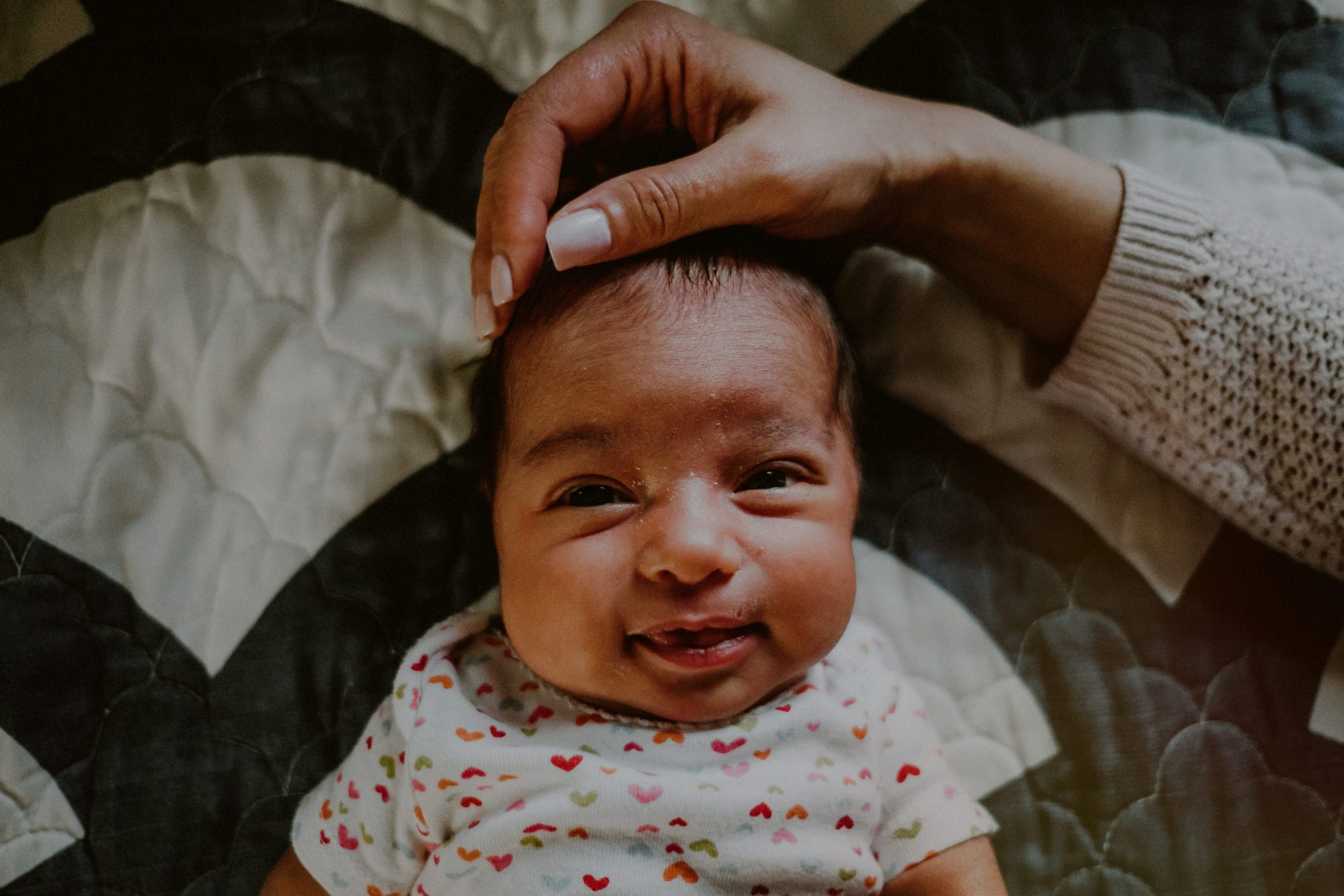 newborn baby looking up with mother's hands on head