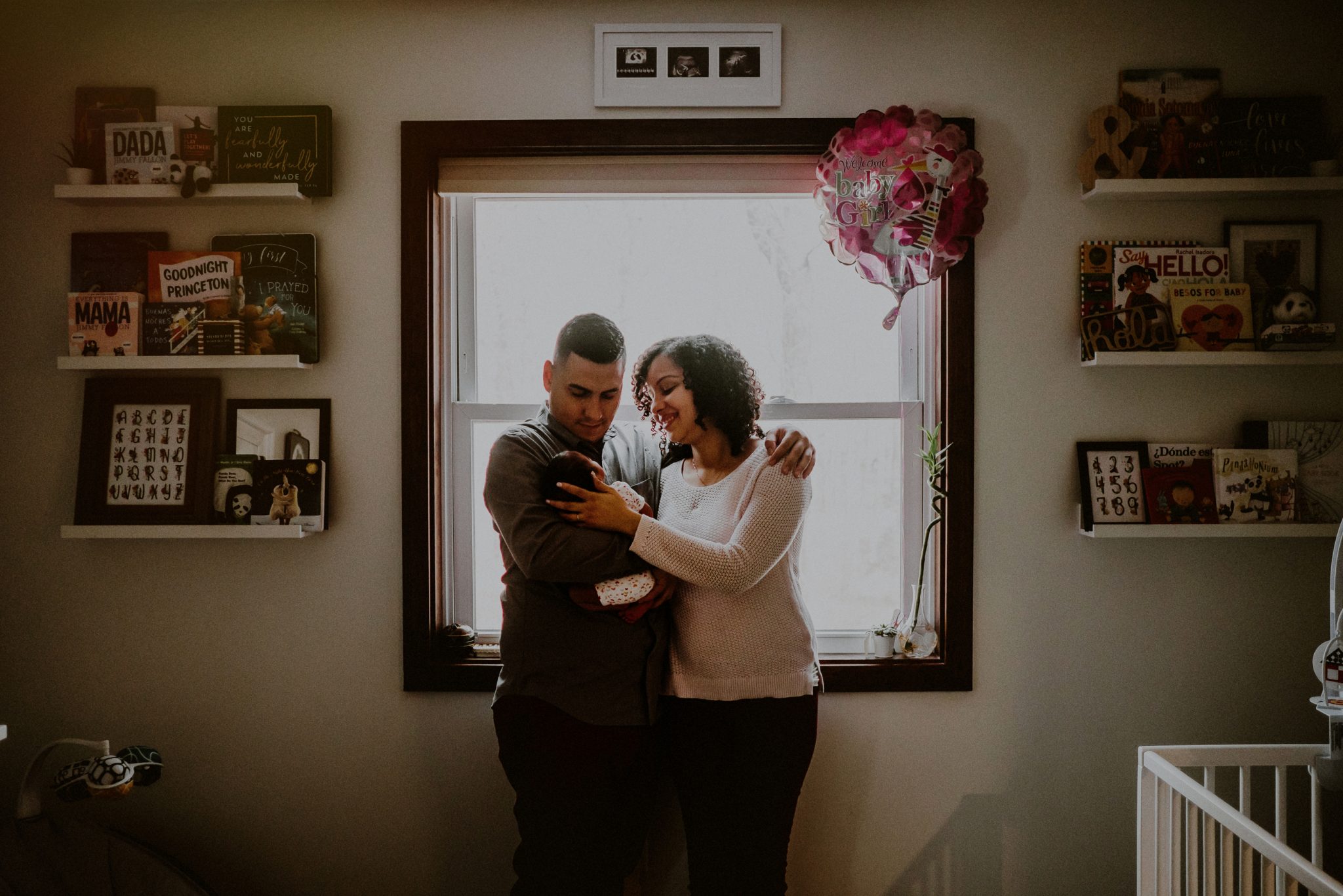 environmental portrait of family holding newborn in baby's bedroom