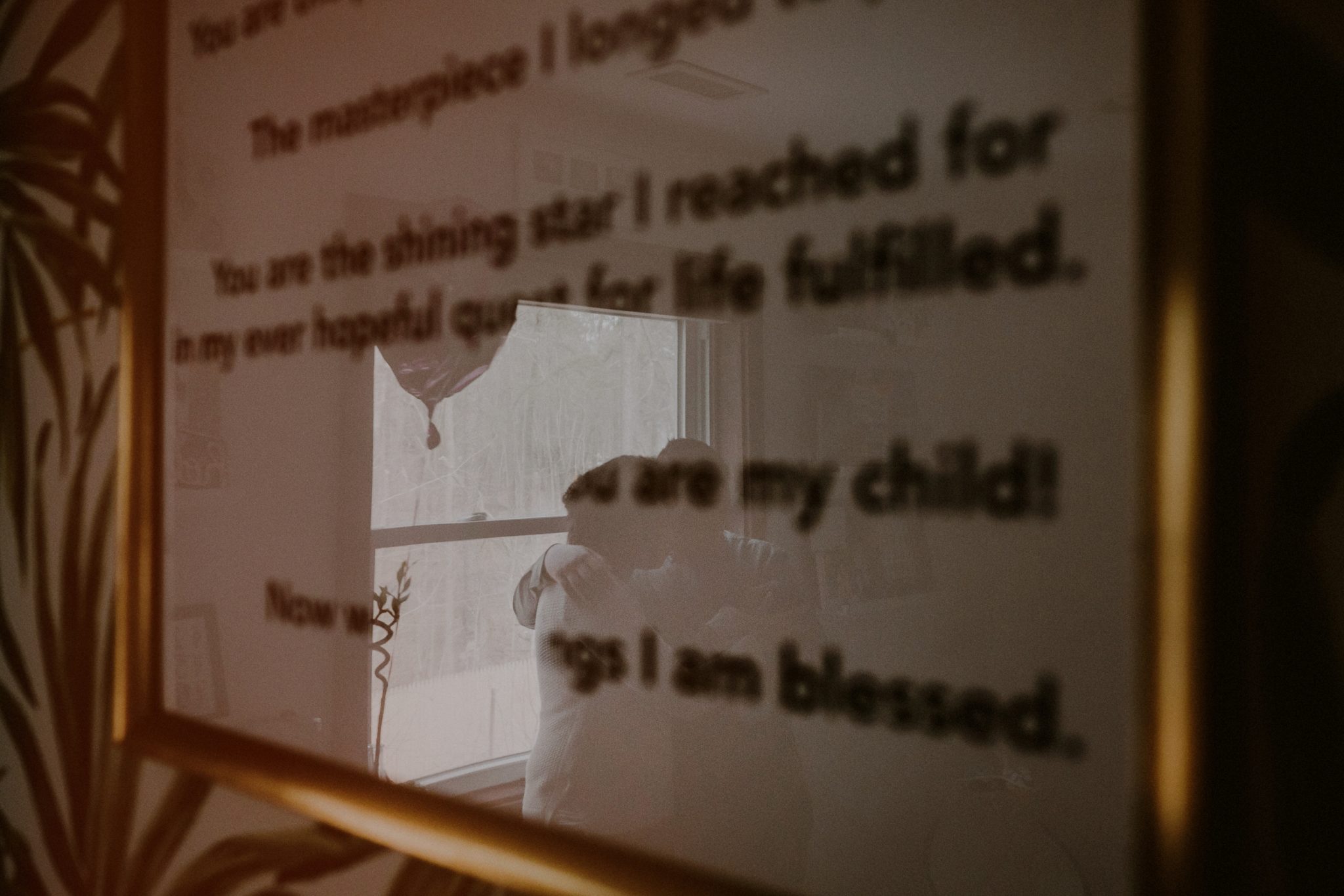 reflection of family portrait seen through biblical quote on framed print on wall