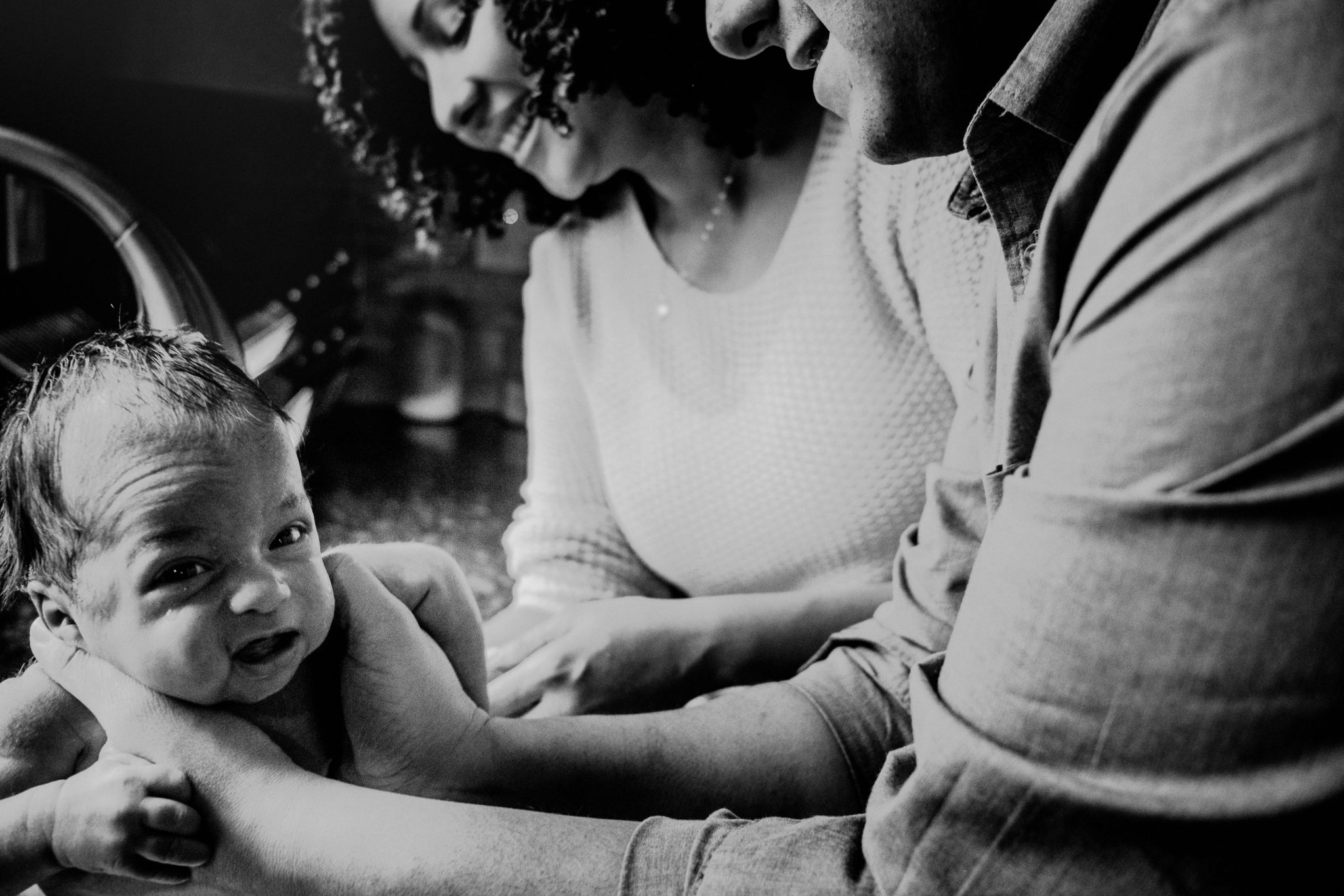 documenting baby's first bath and parent's expressions in black and white photo