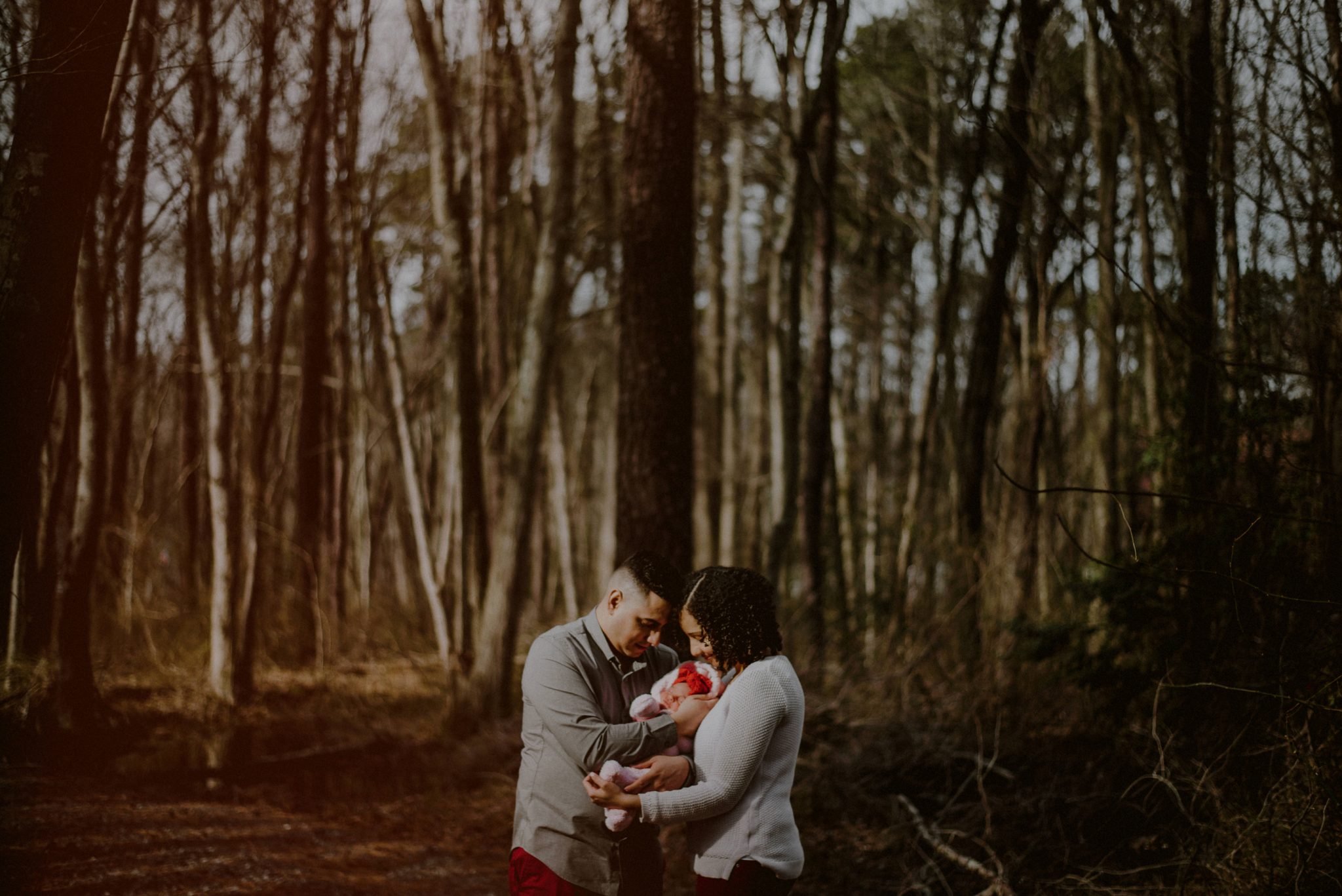 rustic outdoor family portrait in the woods with newborn surrounded by bare winter trees