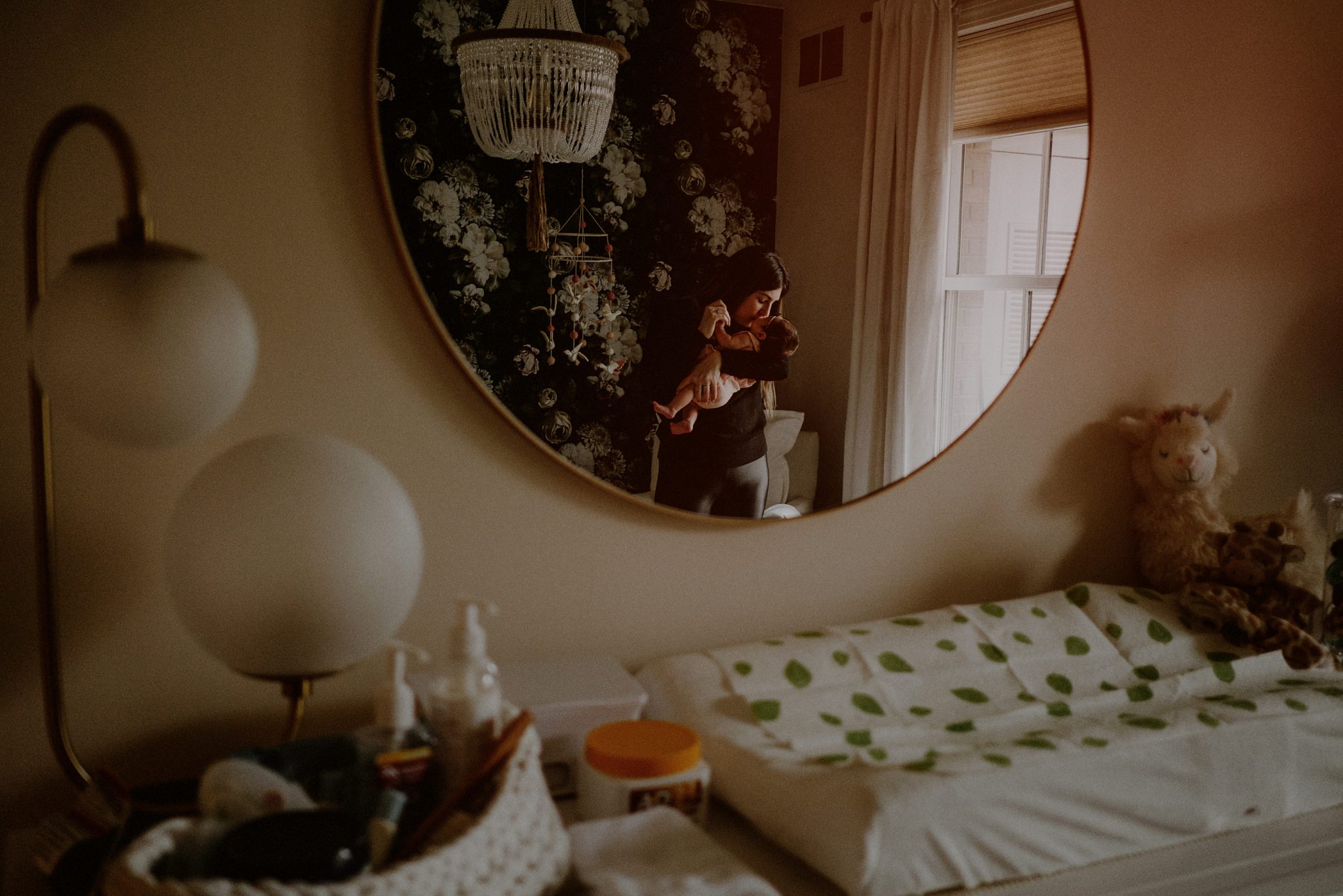 mother holding baby in reflection of mirror in baby's room