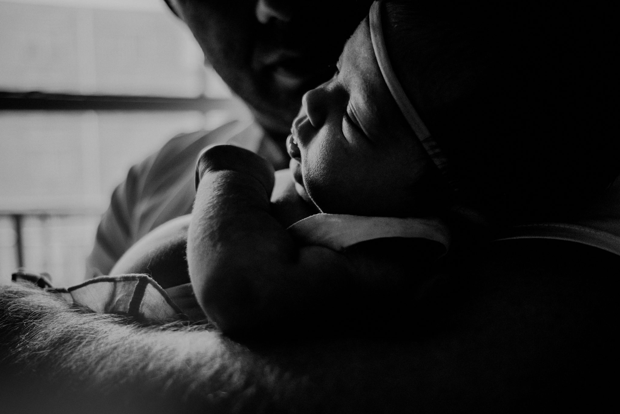 father's arm in foreground of black and white image holding baby
