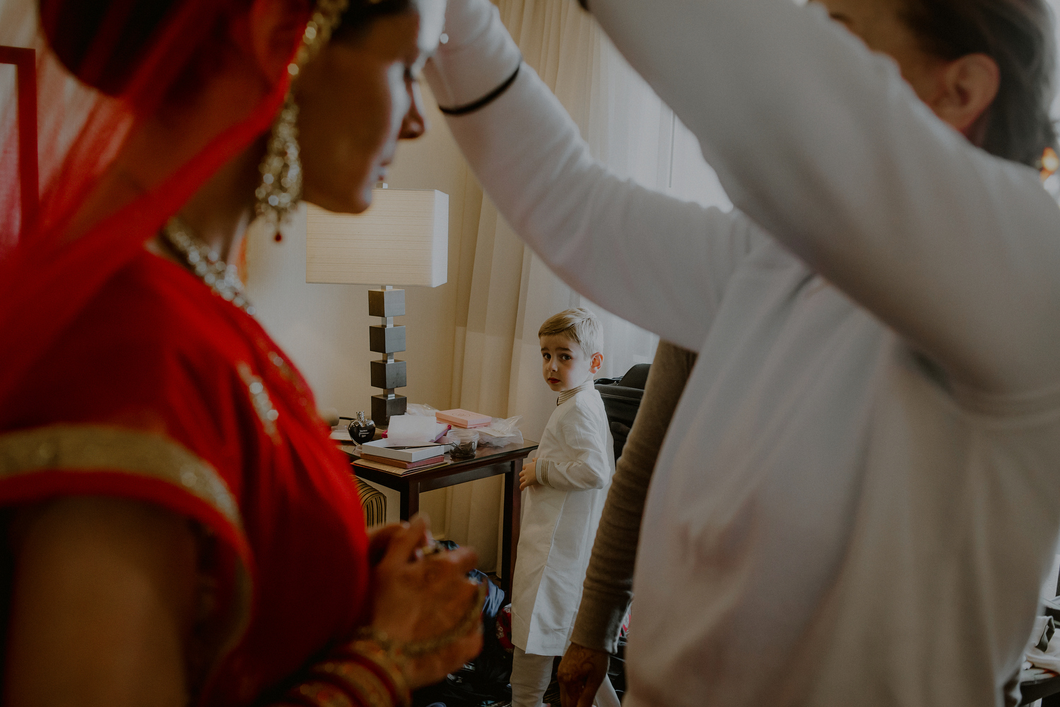 little boy looking on as indian bride gets dressed