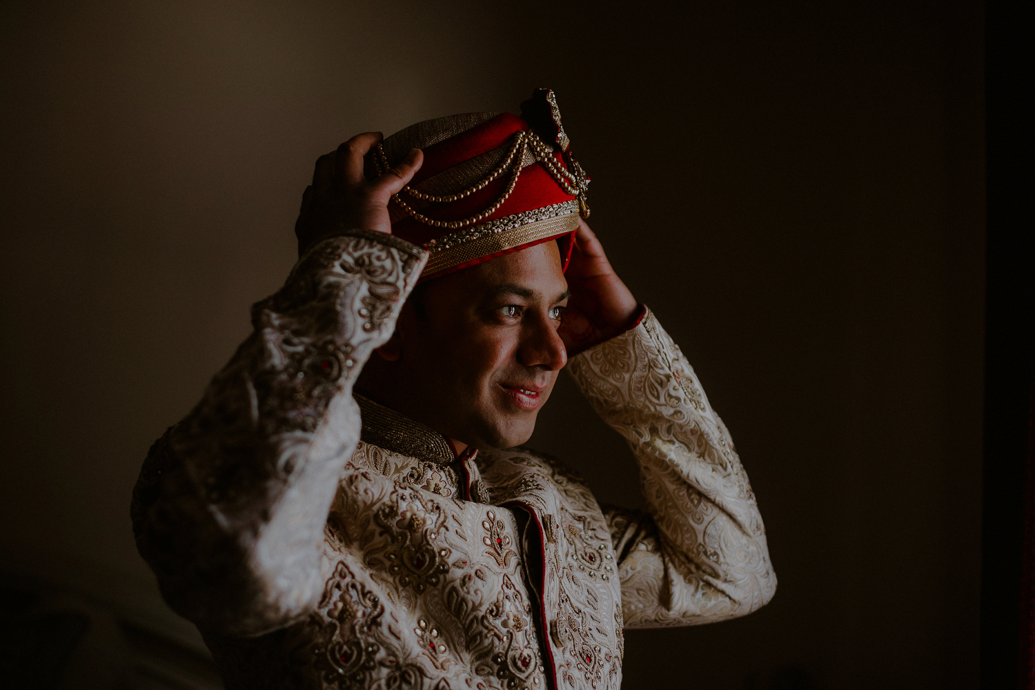 indian groom putting on turban and other indian groom attire