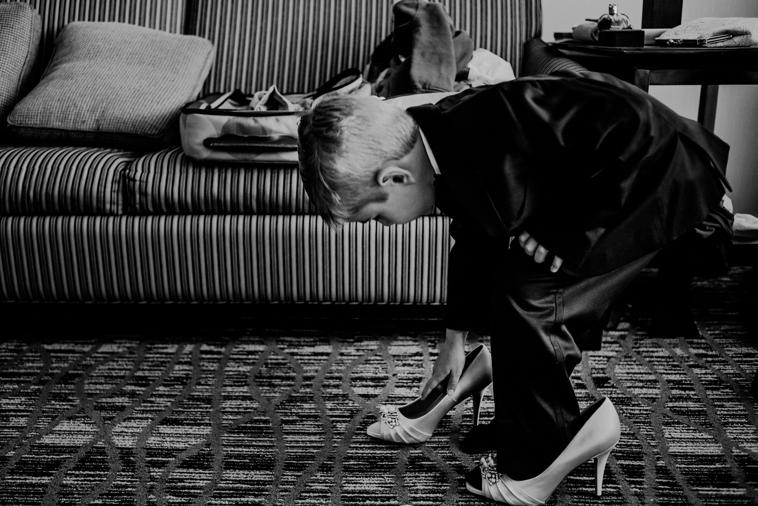 boy playing with bride's wedding shoes