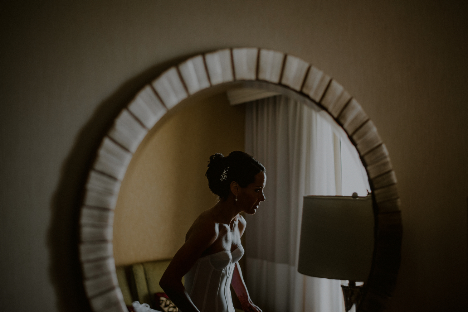 bride getting ready in reflection of mirror of hotel room