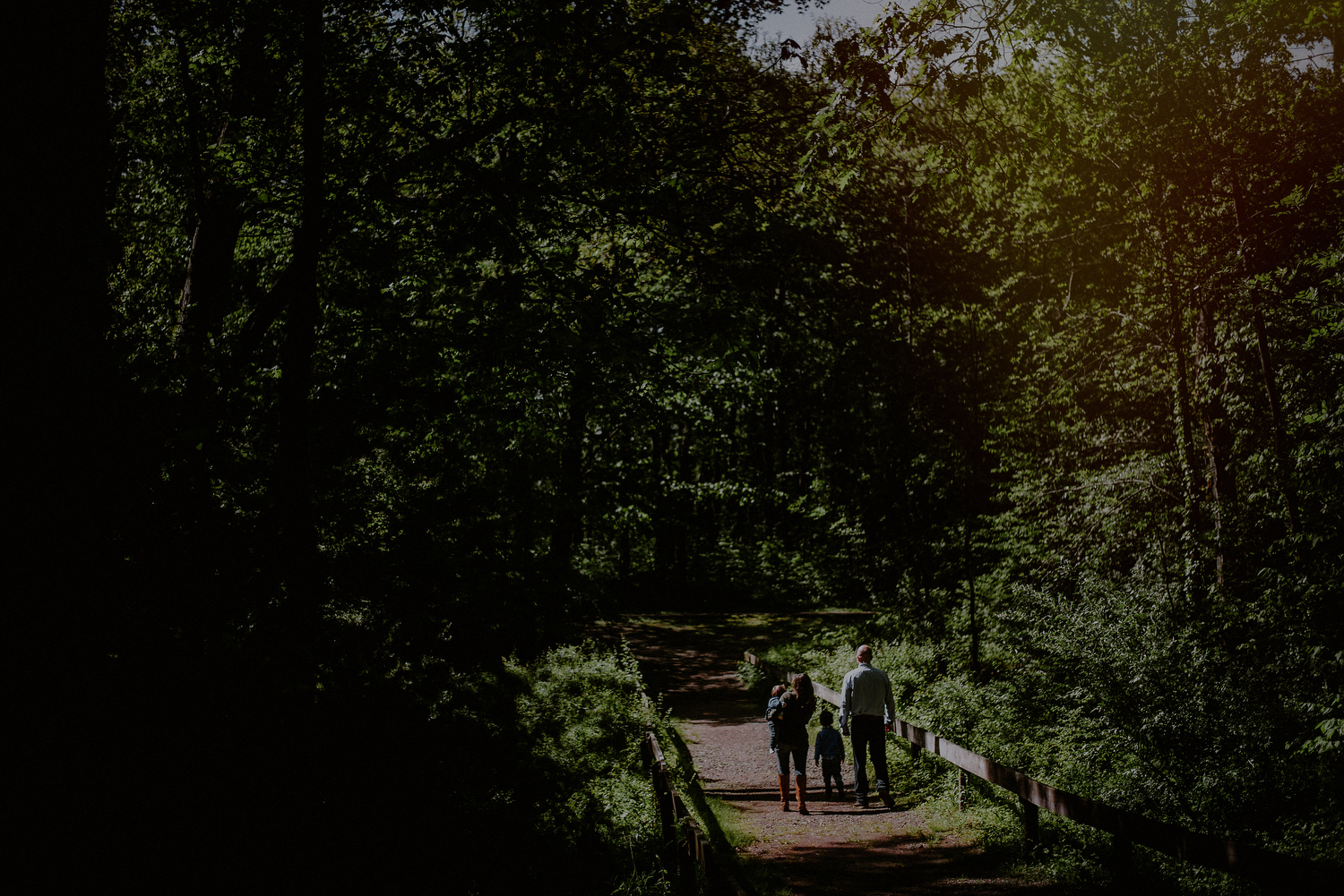 creative spring family photo of family crossing bridge in the sunlight