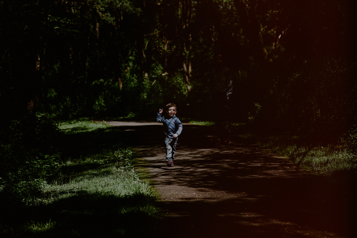 rambunctious boy running in sunlight in park
