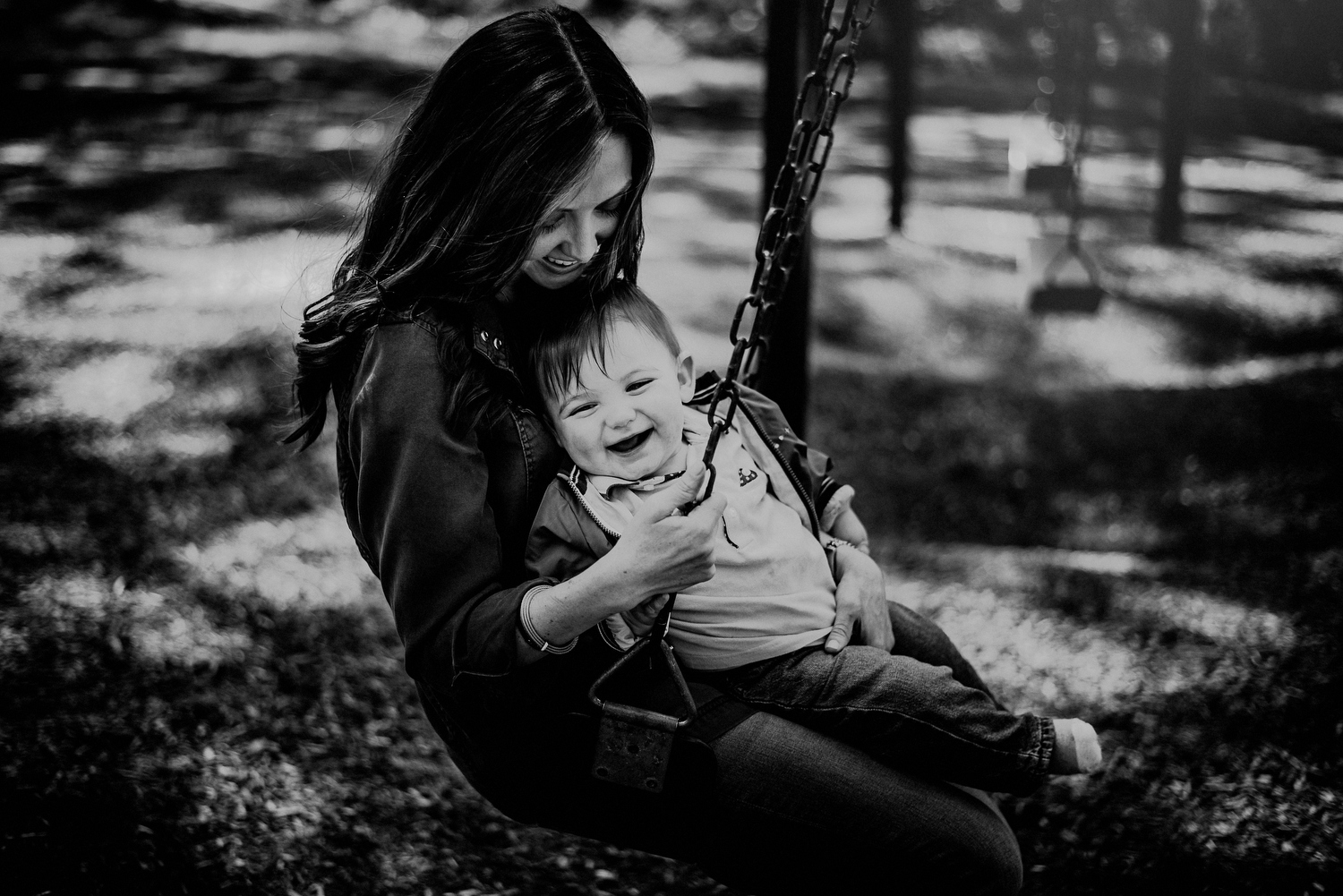 moment between mom and son on swingset in black and white photograph