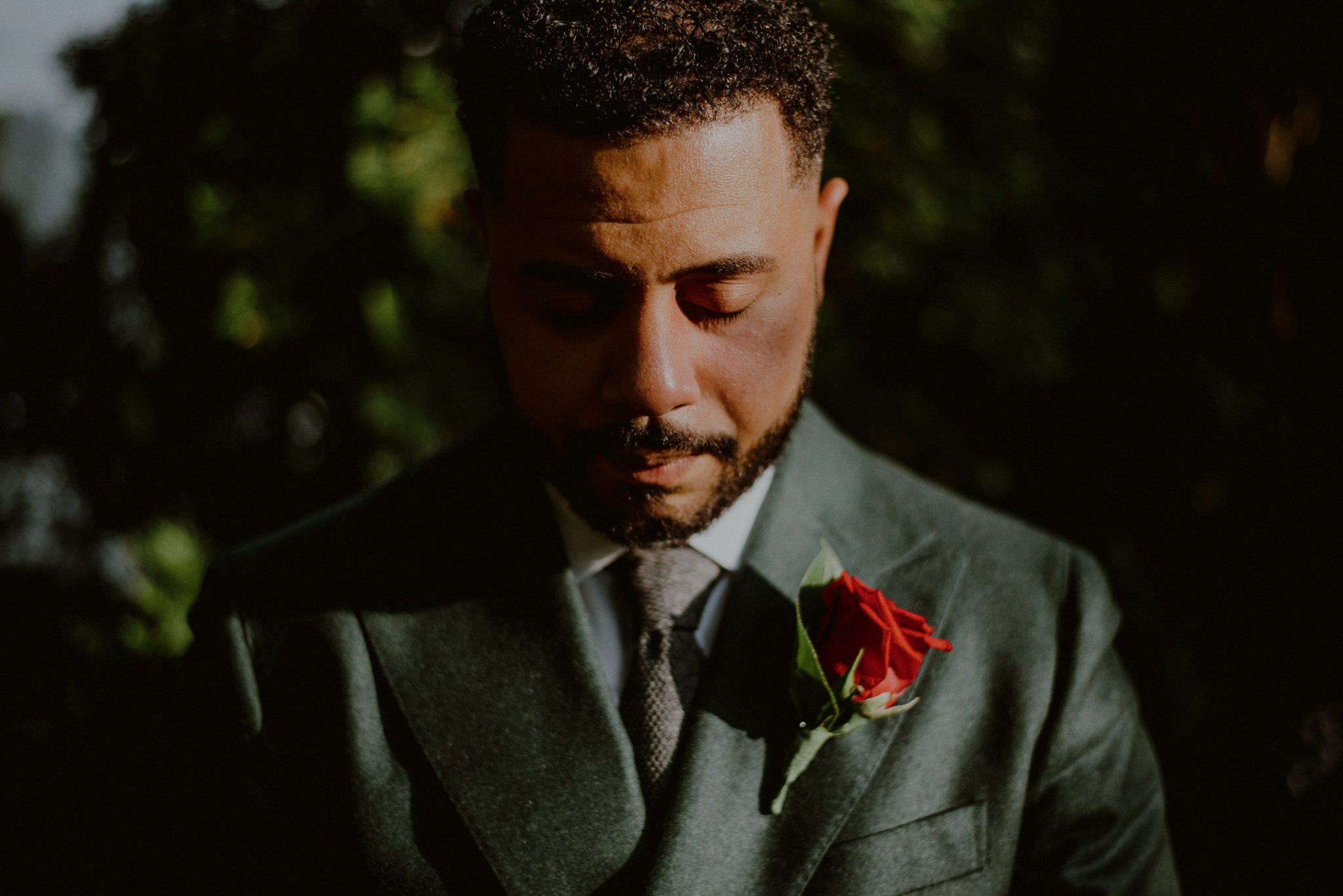 creative groom portrait in sunlight wearing green suit