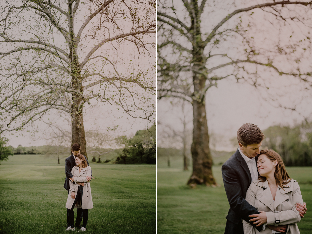 couple embraces in front of tree at Natirar park in rainy weather