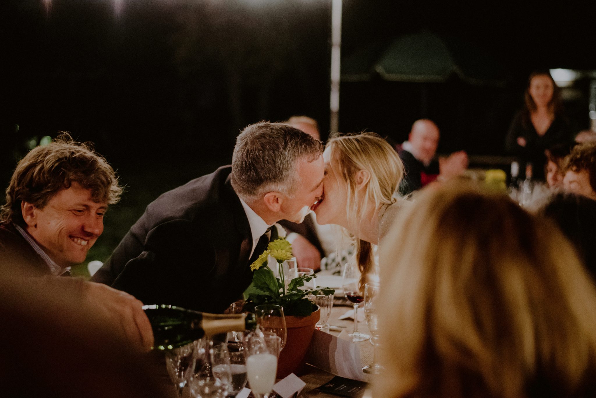 candid kiss between bride and groom during dinner