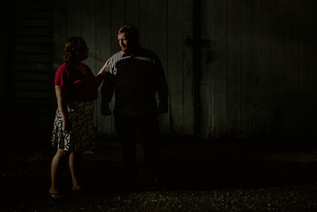 engaged couple poses dramatically in sunlight and shadow