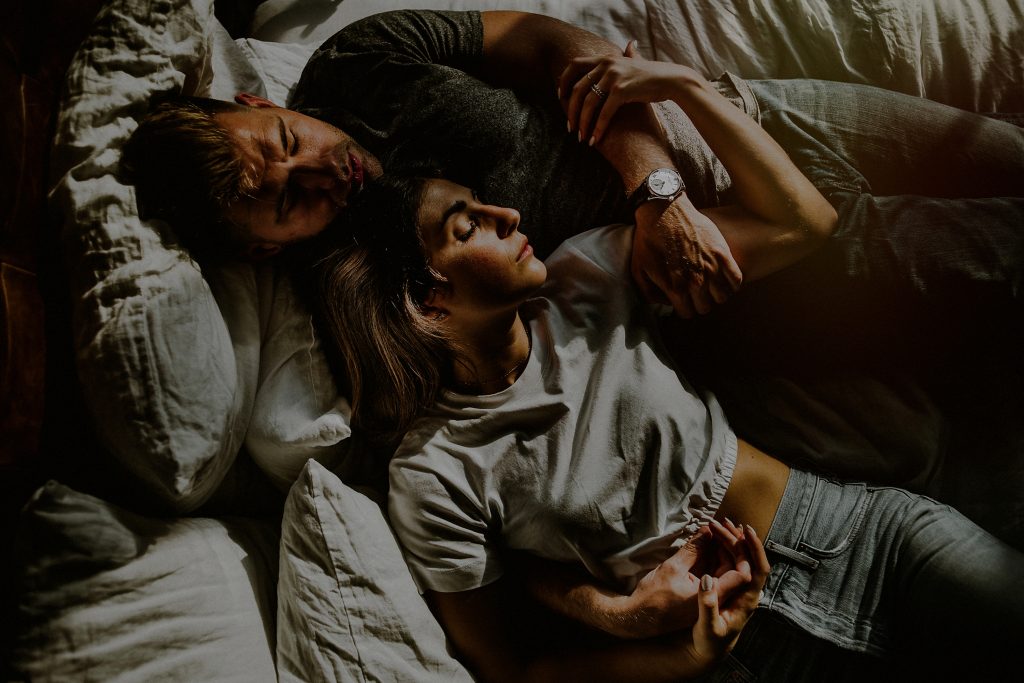 couple dramatically embraced in engagement photos on bed