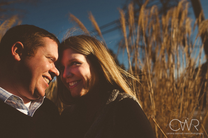 winter engagement photos, couple in field smiling on sunny december day