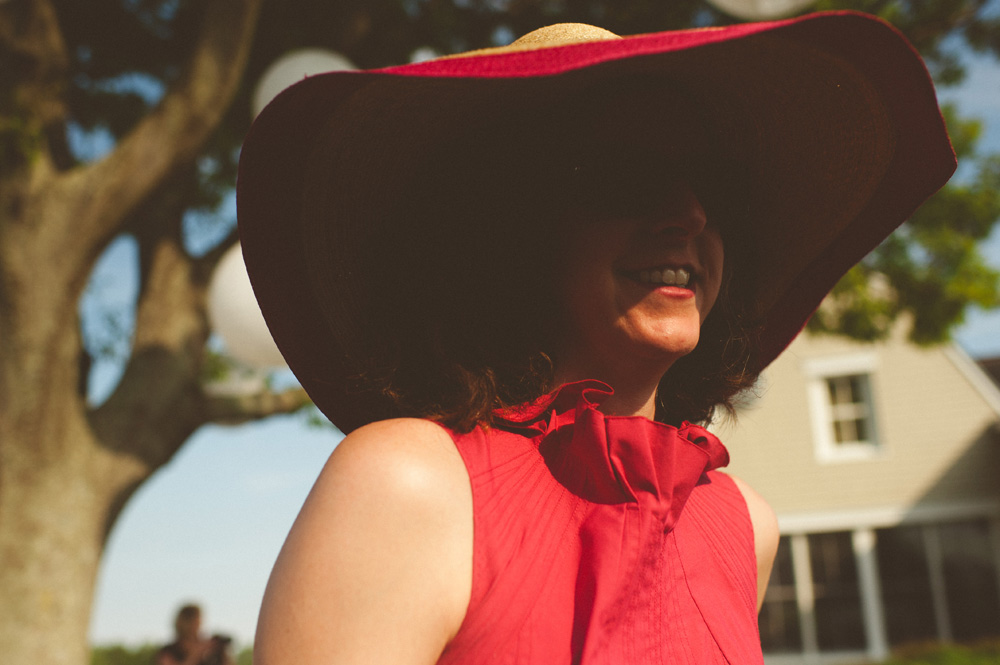 destination wedding photographer, guest with bright red large hat and red lipstick smiling