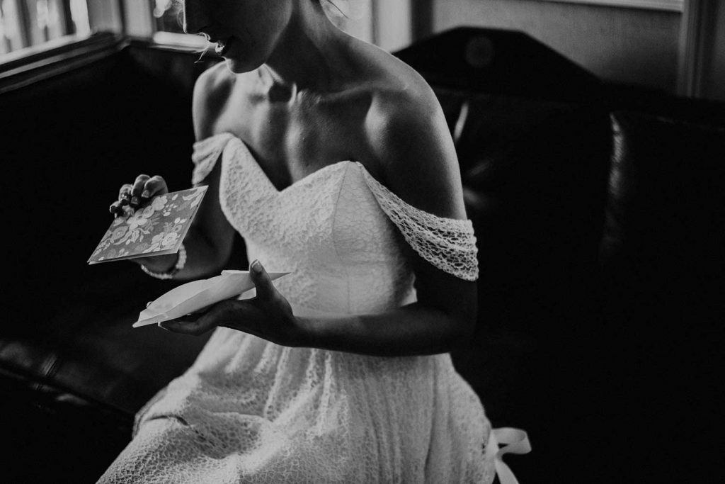 bride reads wedding card in her wedding dress