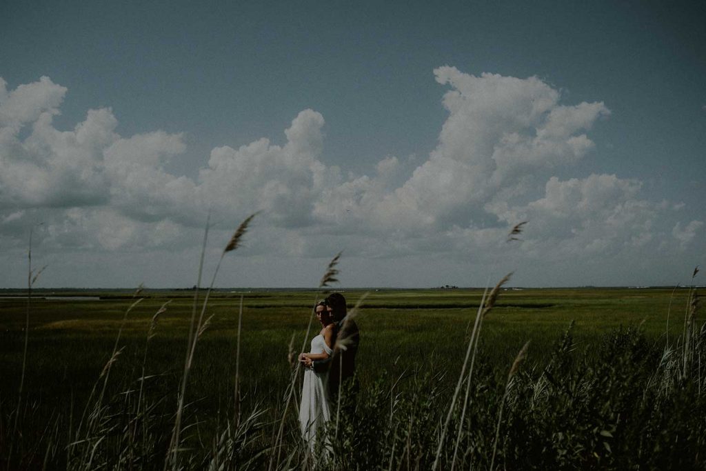 portrait of bride and groom in marsh with clear summer sky