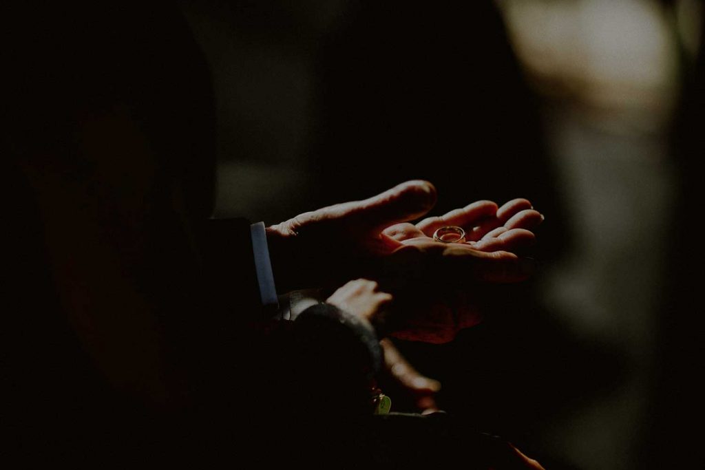 dramatic detail photo of wedding rings held by parents