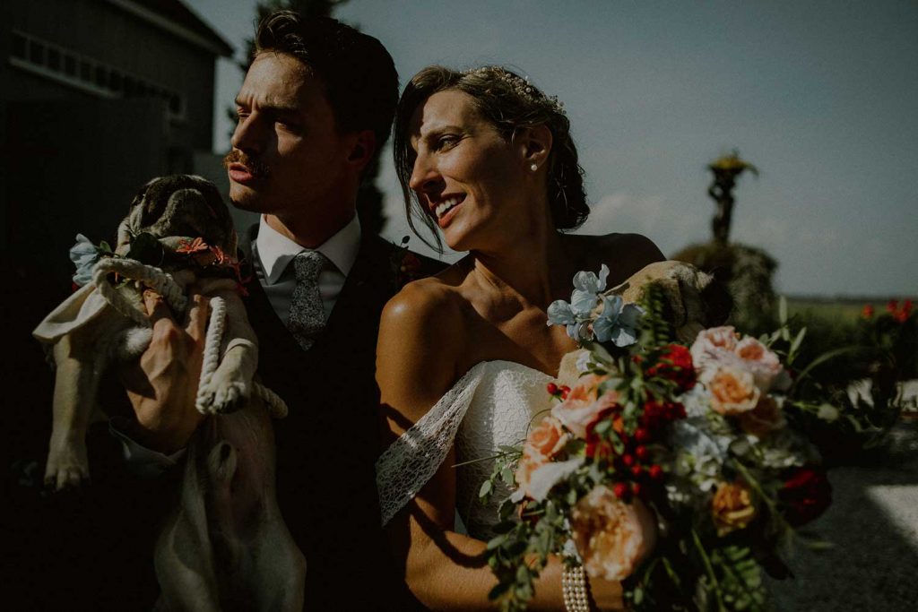 bride and groom pose with dogs at their bonnet island wedding