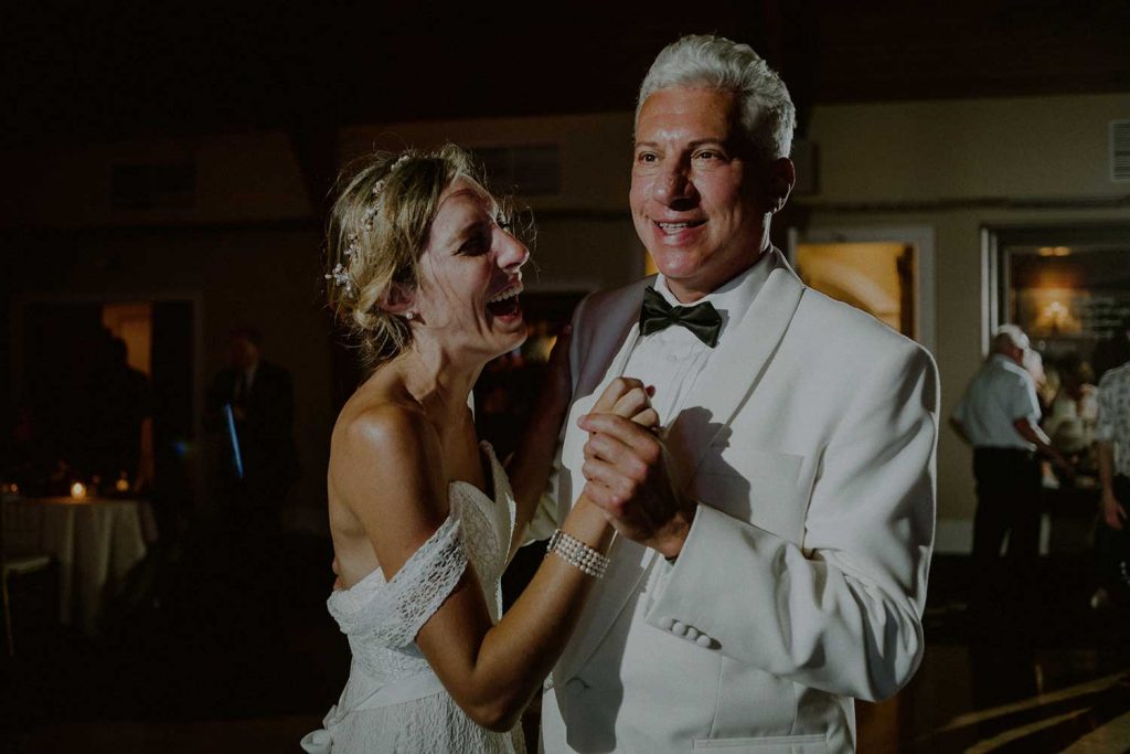 bride and father dance and laugh during wedding reception