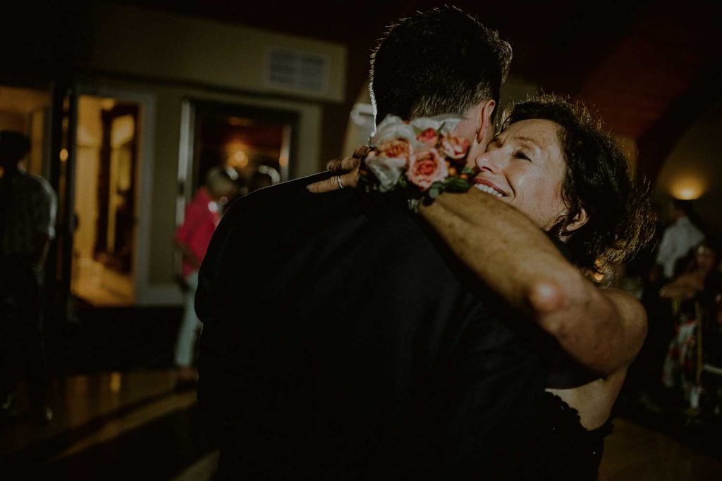 groom and mother dance and smile during wedding reception