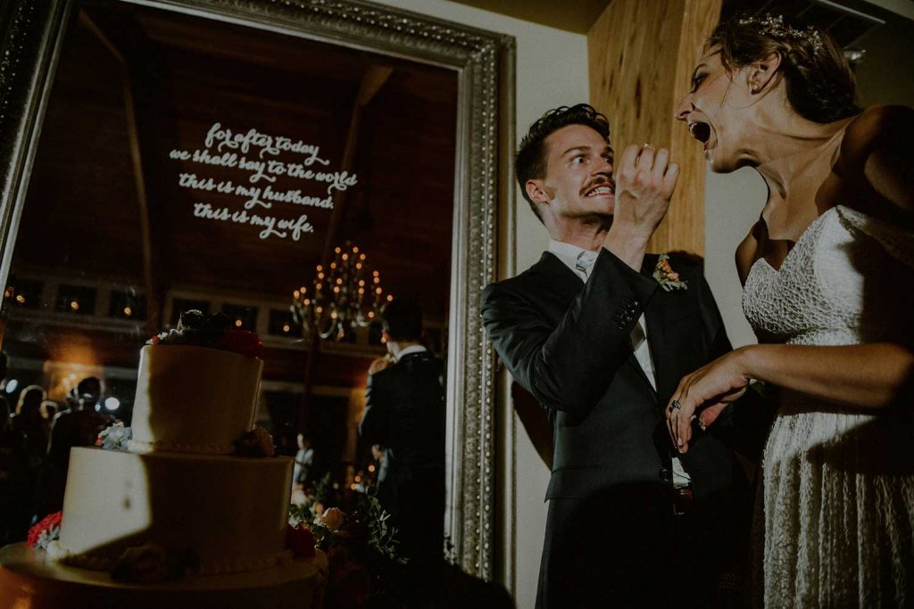 silly moment between bride and groom cutting cake at wedding reception