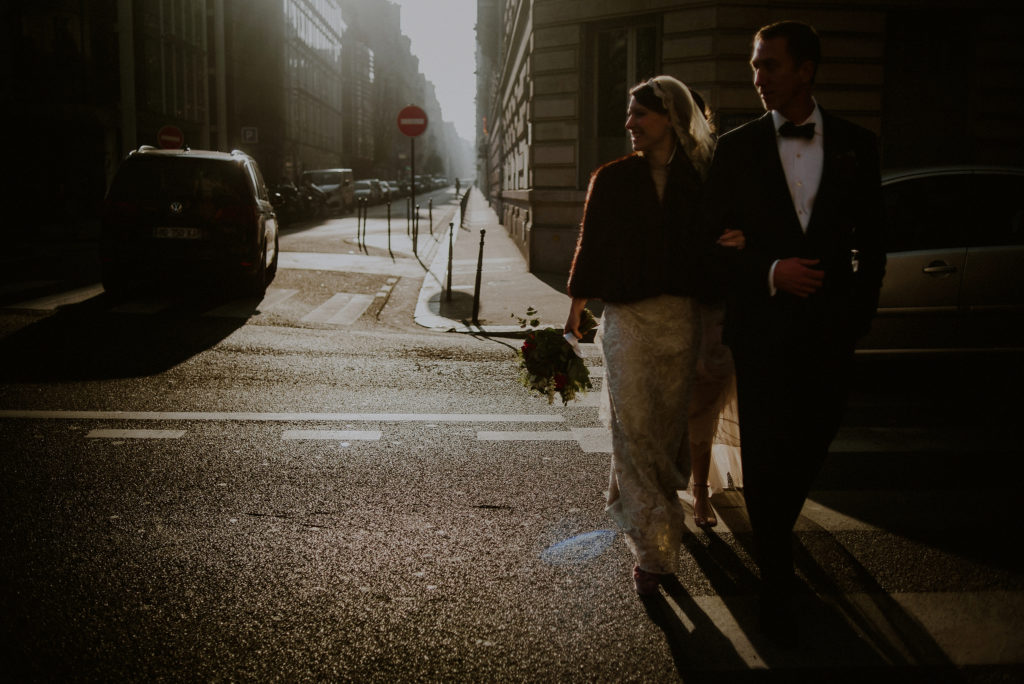 couple in wedding attire walking across paris streets during their paris elopement
