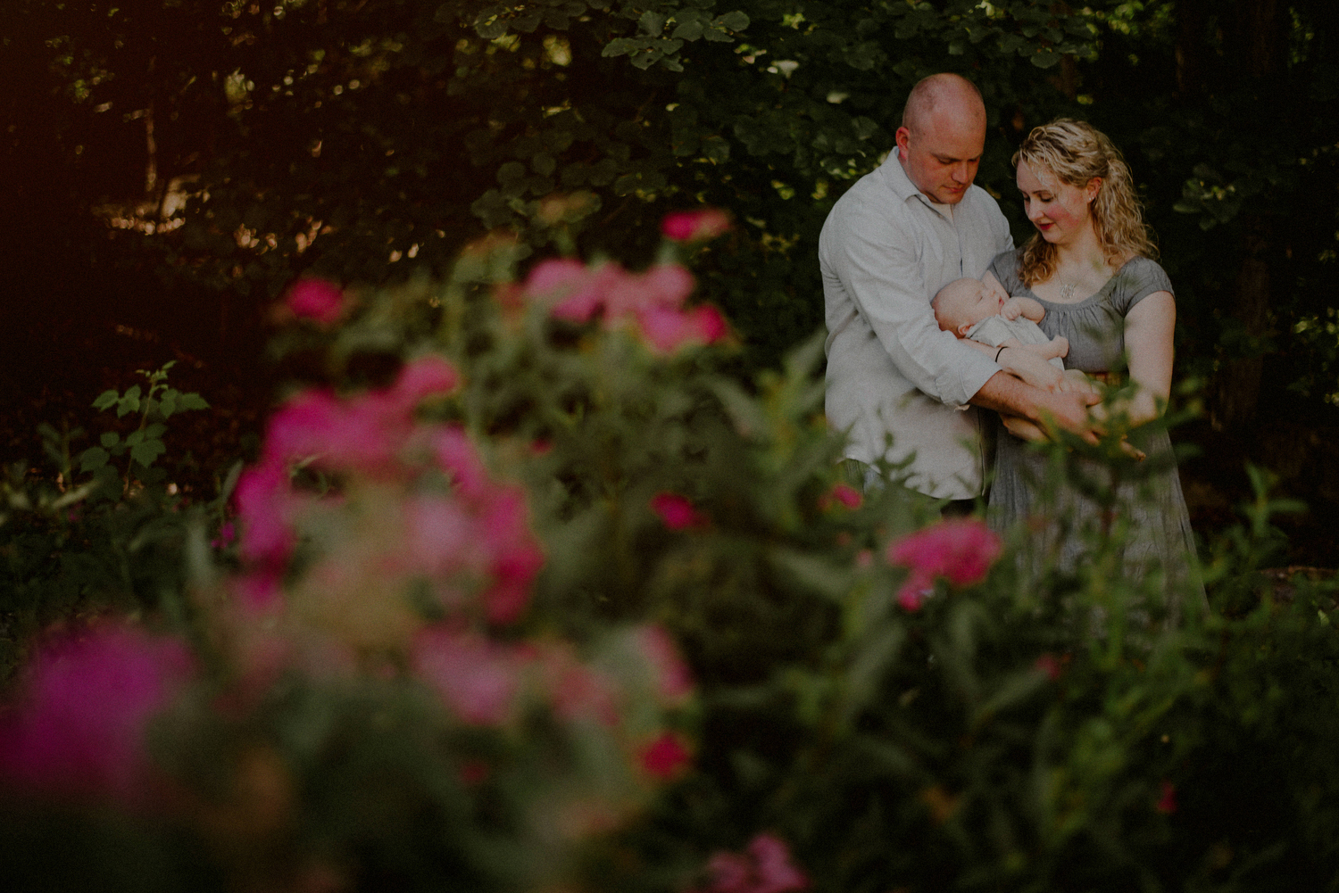 family photograph posed amongst greenery with newborn baby