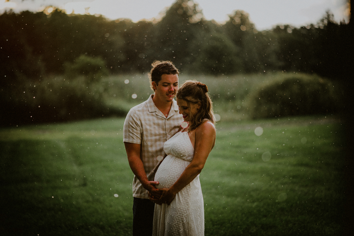 lifestyle image of couple posed in rain with pregnant belly 