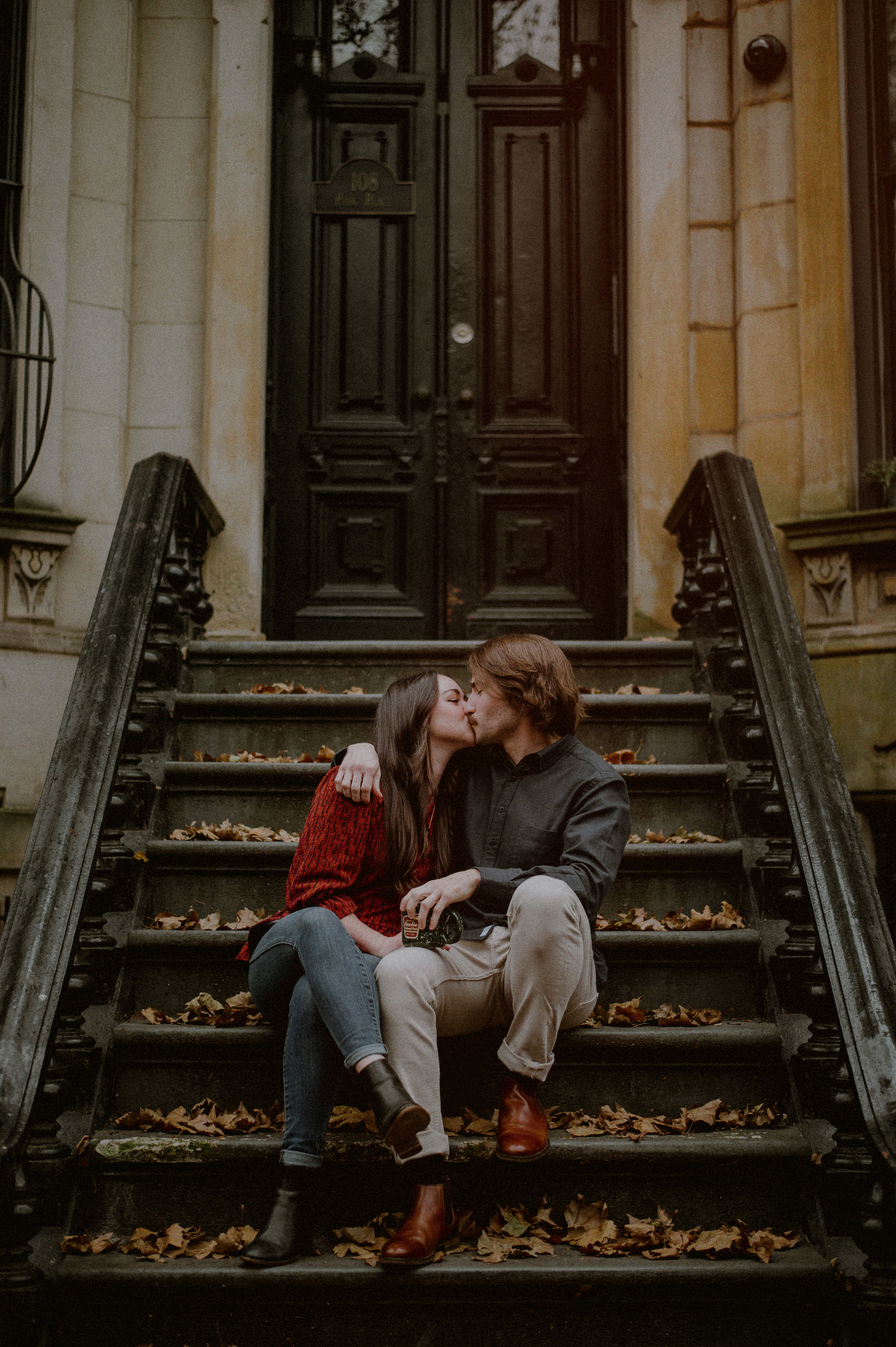 engagement photo of couple sitting outside NYC apartment