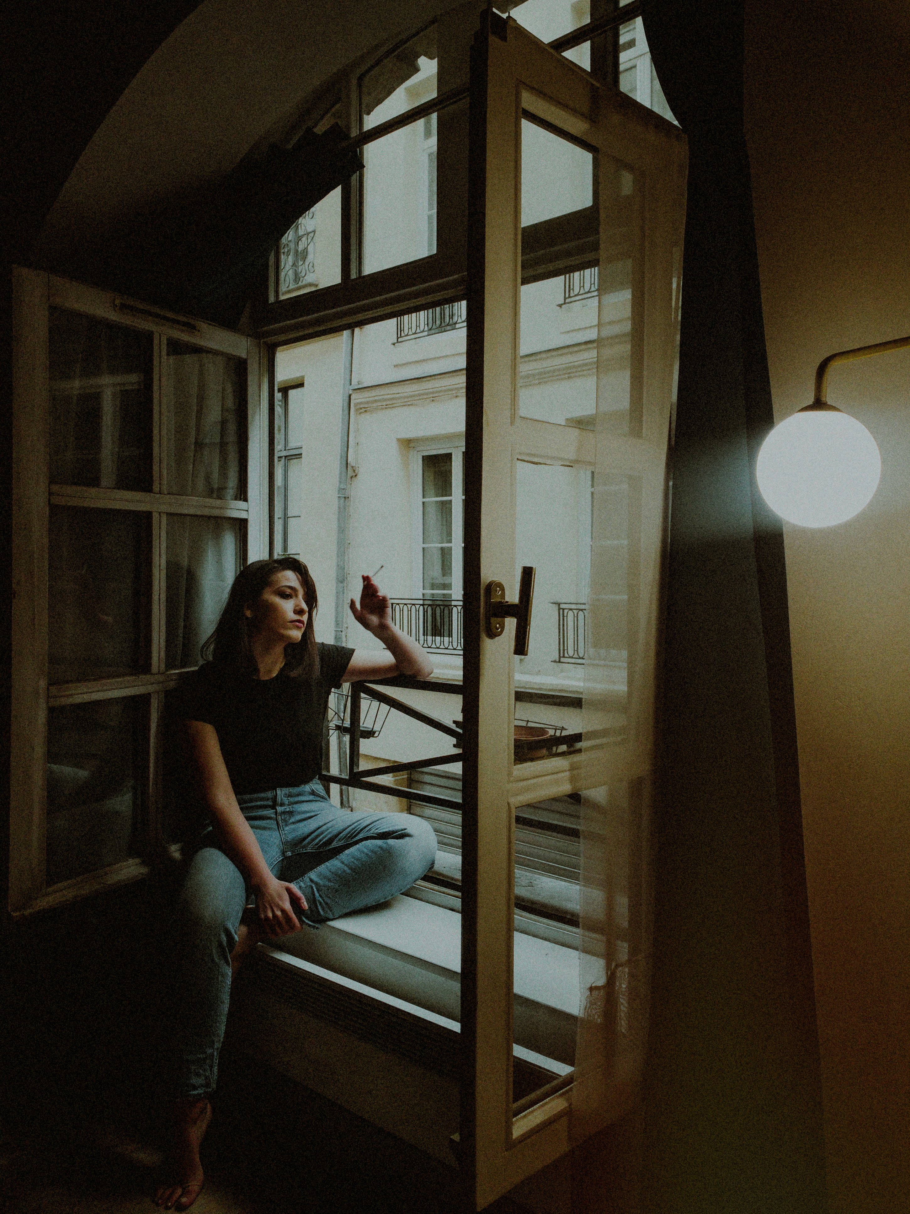 woman on french windowsill smoking cigarette
