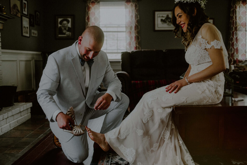 Non traditional wedding photo of groom helping bride getting ready by Carolina Rivera photographer