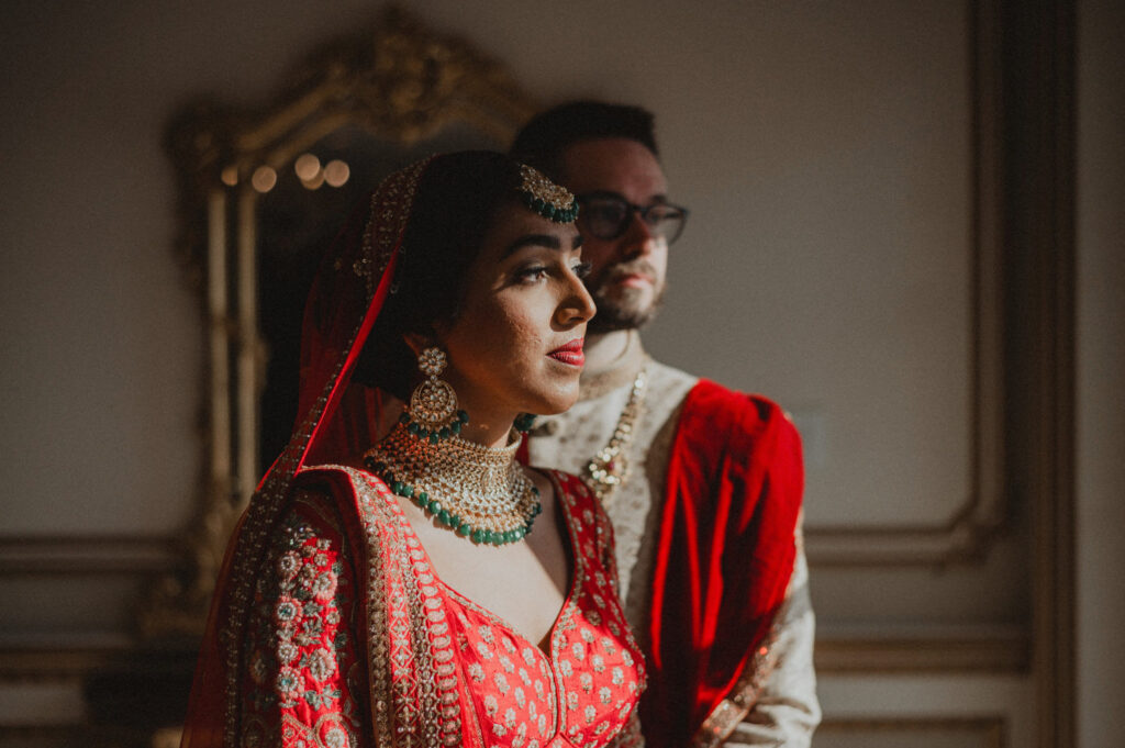 Indian Wedding couple posing in dramatic sunlight dressed in red