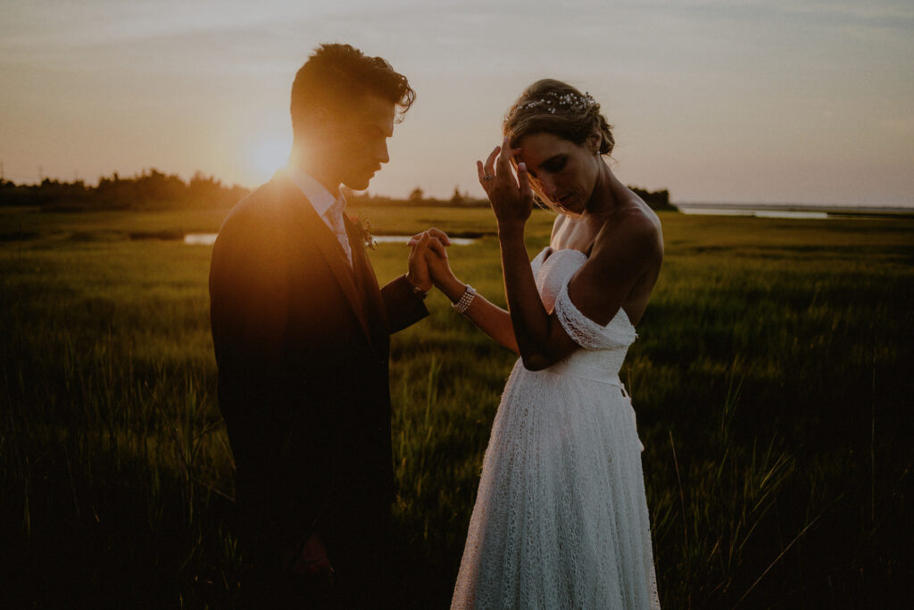 bride and groom candid photo in front of sunset in marshlands - Bonnet Island Estate Wedding Photos