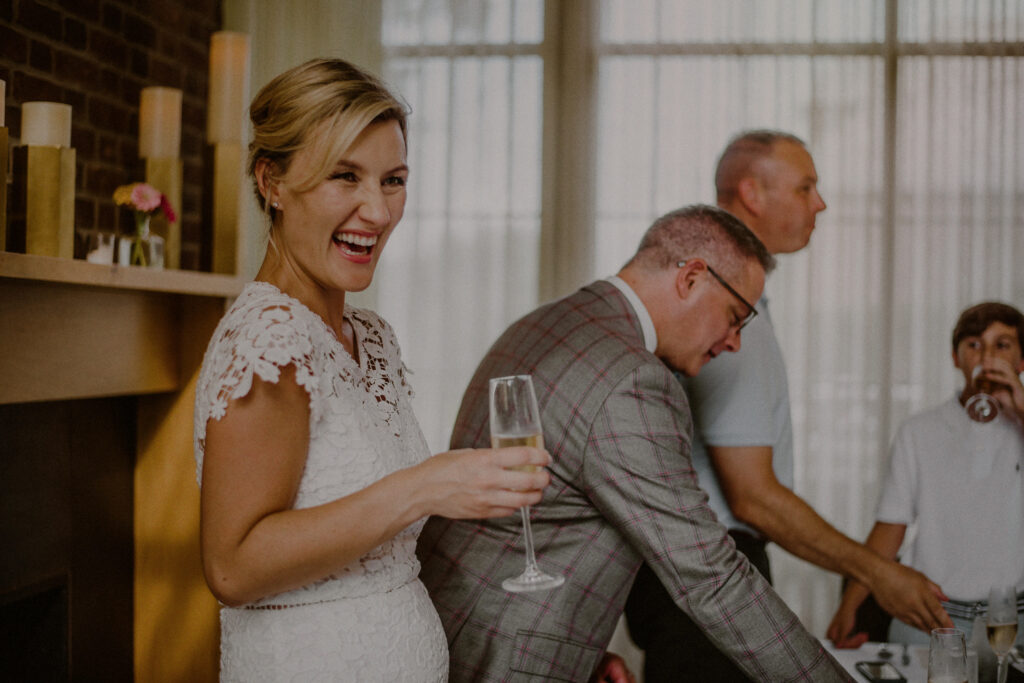 bride laughing with a champagne glass during toast - Mansion at Natirar Wedding Photos