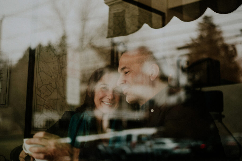 couple having a coffee at a coffee shop, photographed through a window