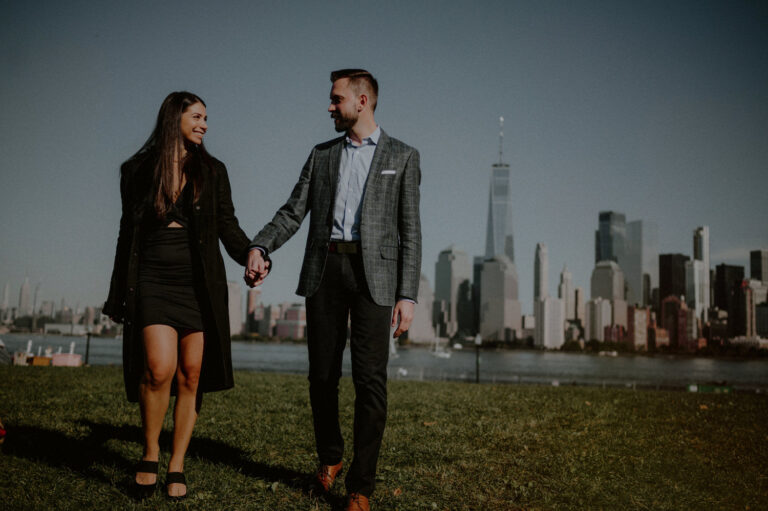 couple walking in front of nyc skyline at liberty state park