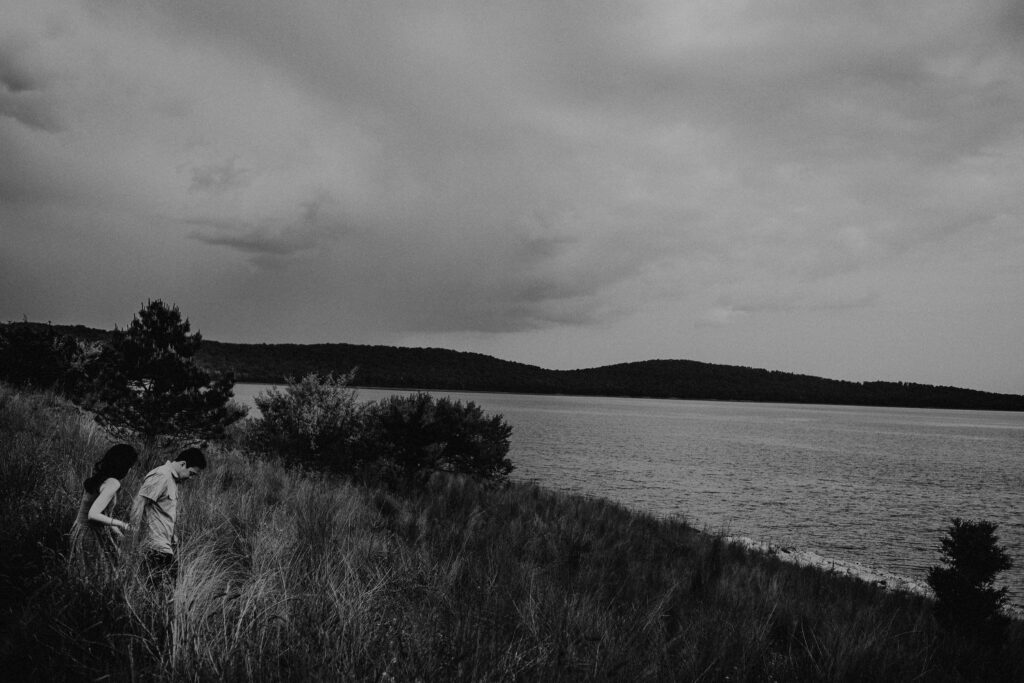 black and white engagement photo from a distance of couple in front of round valley reservoir
