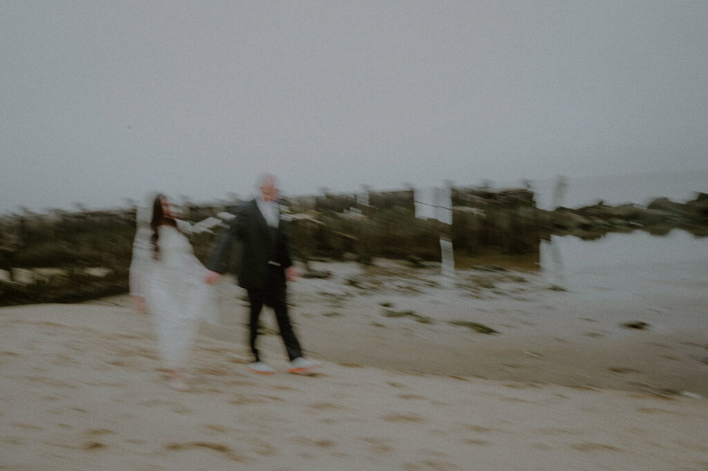 blurry photo of wedding couple walking across beach