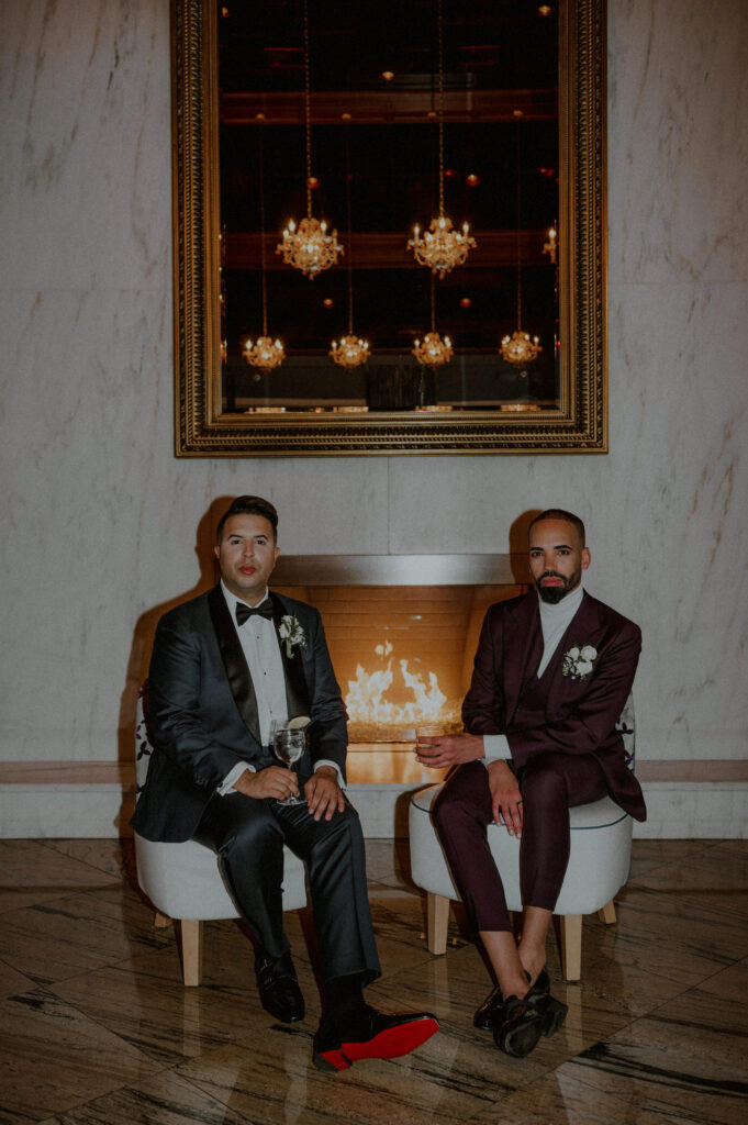 editorial style image of 2 grooms sitting by fireplace in an elegant setting