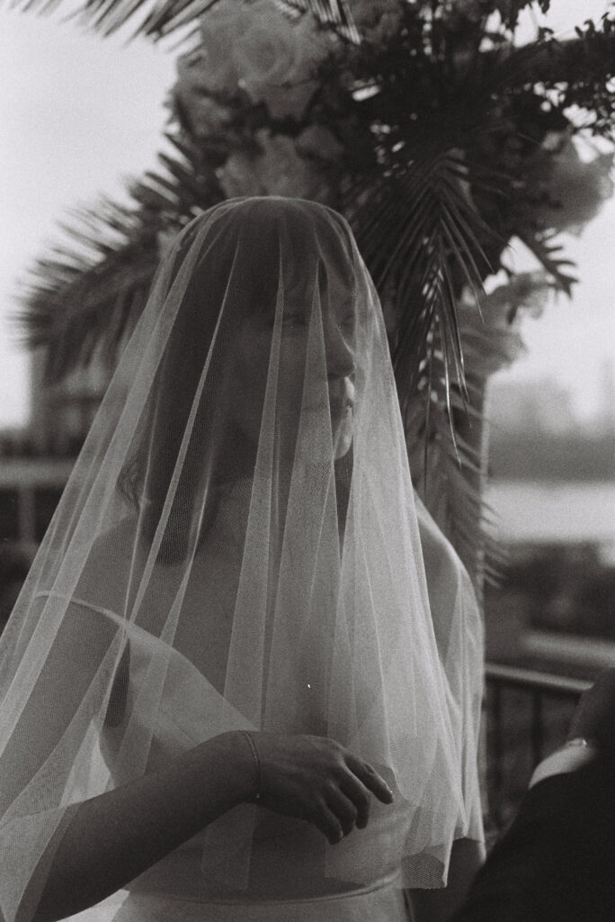 black and white film image of bride covered by veil during wedding ceremony
