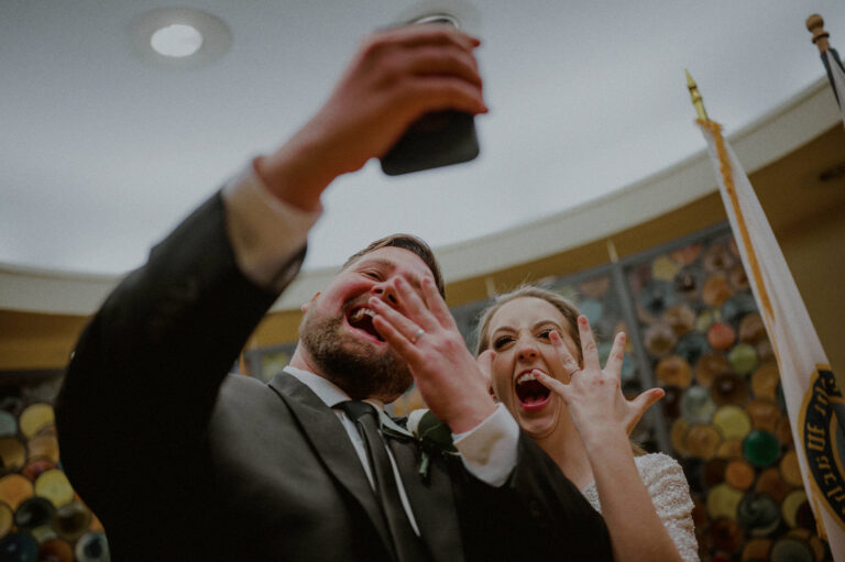couple enthusiastically showing off wedding rings at city hall elopement