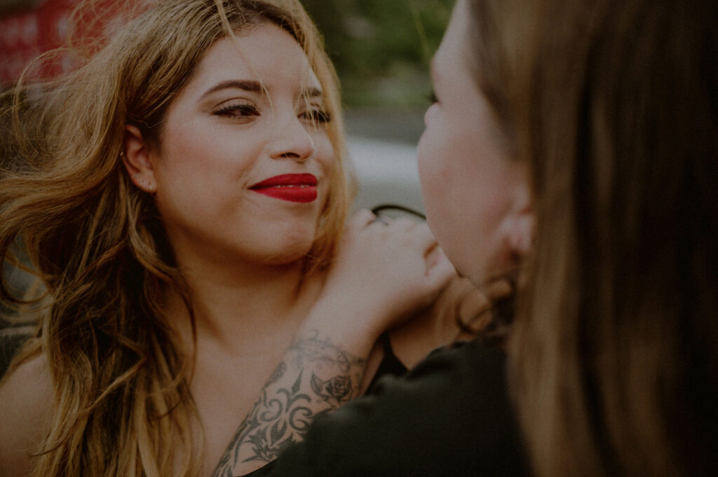 same sex couple looking lovingly at each other while wind blowing in face