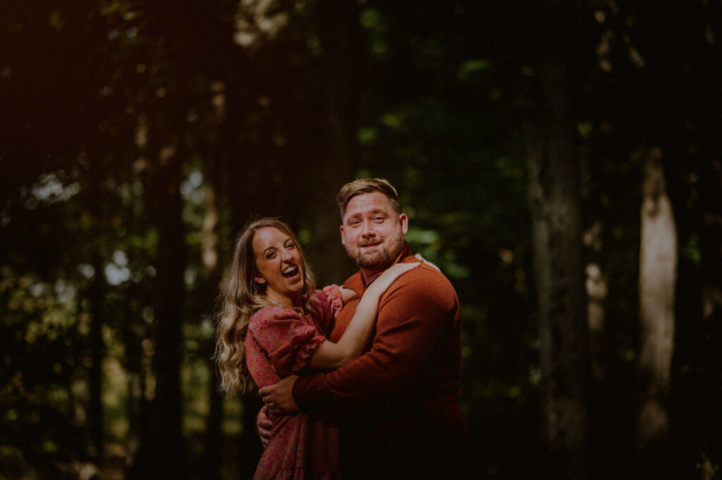 couple joyfully laughing together in the middle of the woods