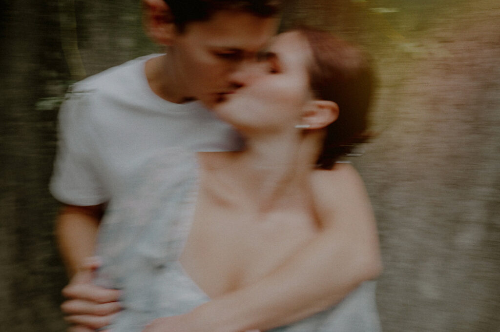 engagement photo incorporating camera blur of couple kissing
