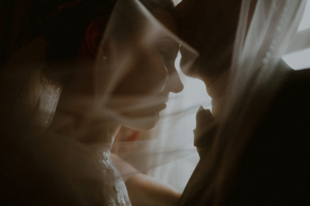 intimate photo of bride and groom kissing behind a veil