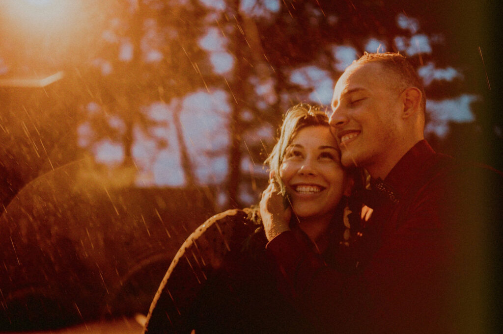 bride and groom smiling in the rain at dusk